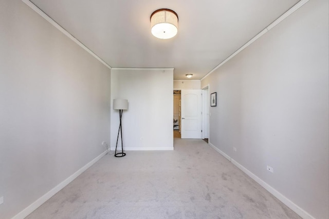 empty room with baseboards, light colored carpet, and ornamental molding