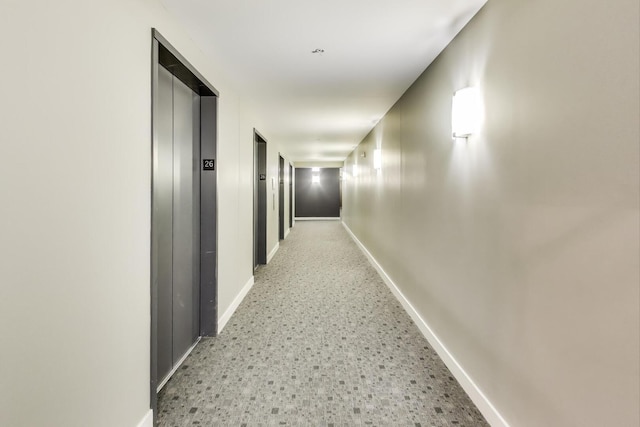 hall with baseboards and elevator