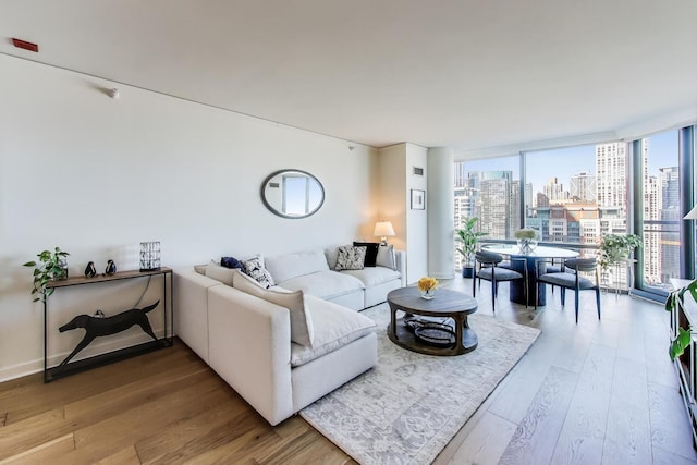 living room with expansive windows, a view of city, baseboards, and wood finished floors