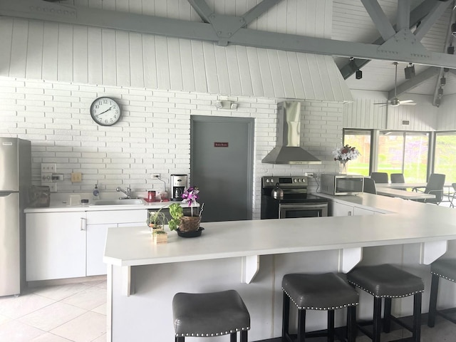 kitchen with light countertops, a sink, wall chimney range hood, and stainless steel appliances