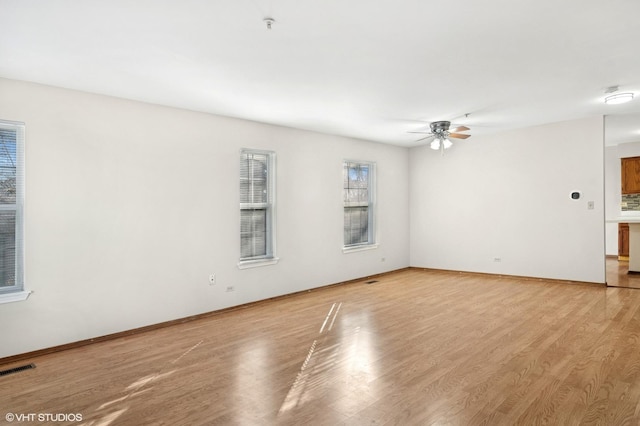 unfurnished room with light wood finished floors, ceiling fan, visible vents, and baseboards