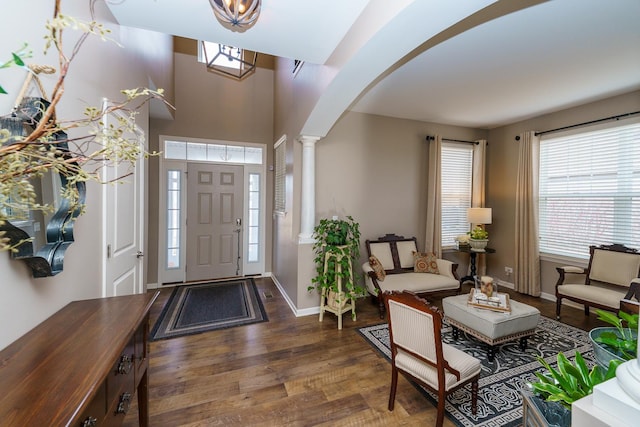 entryway featuring ornate columns, arched walkways, a wealth of natural light, and wood finished floors