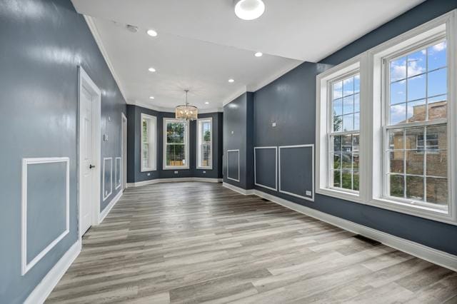 spare room with crown molding, light hardwood / wood-style floors, and a chandelier