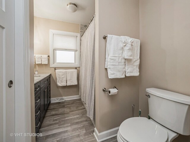 full bath with wood finished floors, a shower stall, vanity, and baseboards