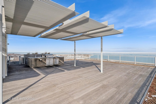 wooden terrace featuring a water view, a beach view, and an outdoor kitchen