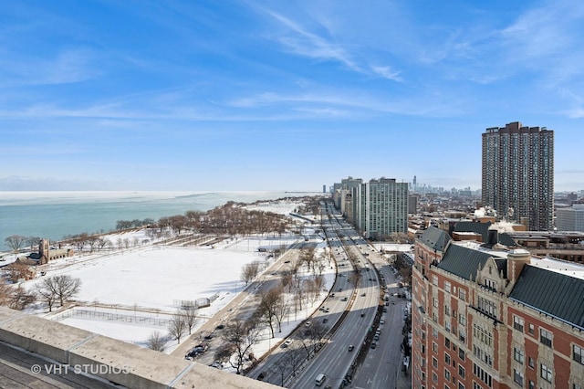 snowy aerial view with a water view and a city view