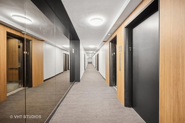 hall with elevator and light colored carpet