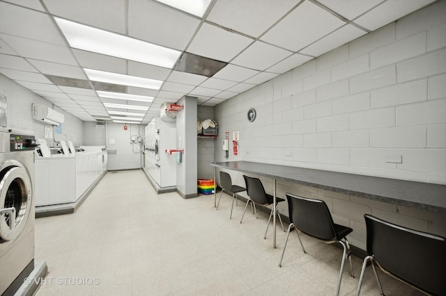 interior space with light floors, washing machine and dryer, and an AC wall unit