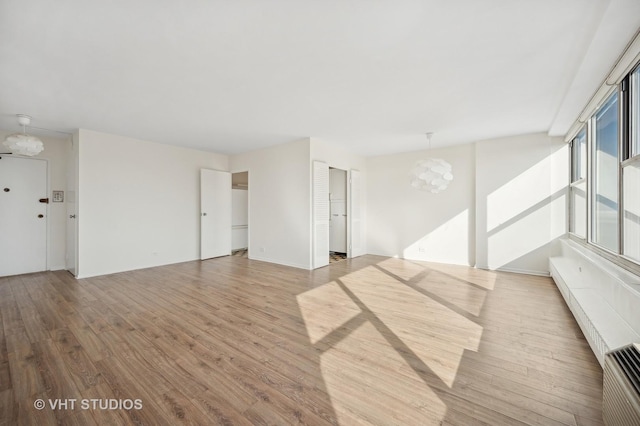 spare room with a chandelier and light wood finished floors