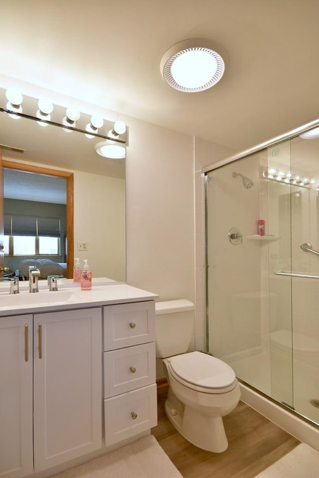 bathroom featuring an enclosed shower, hardwood / wood-style floors, vanity, and toilet