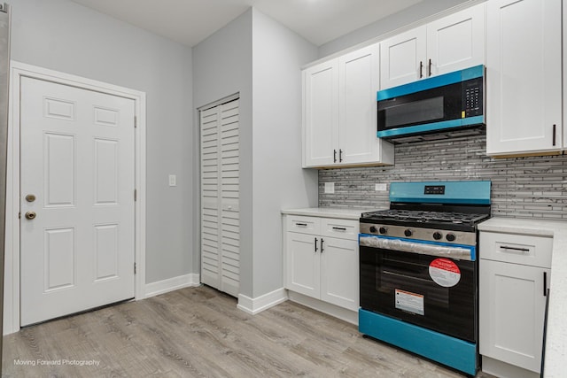 kitchen featuring stainless steel gas stove, tasteful backsplash, white cabinets, and light wood-type flooring