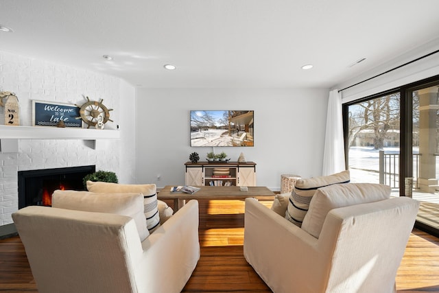 living room with a brick fireplace and hardwood / wood-style flooring