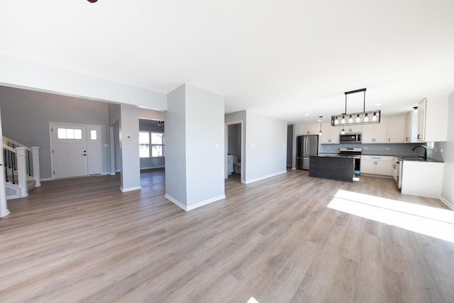 unfurnished living room featuring sink and light hardwood / wood-style flooring