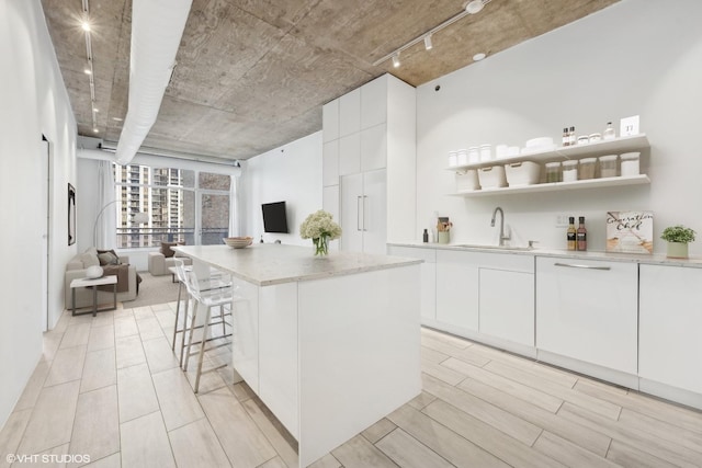 kitchen with white cabinets, a center island, sink, and rail lighting