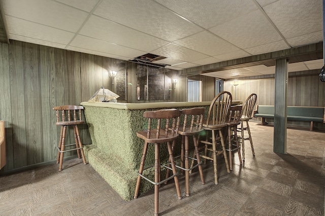 bar featuring a paneled ceiling and wooden walls