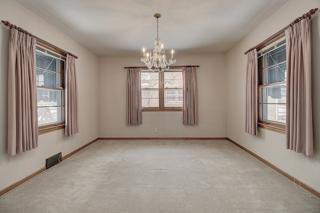 carpeted empty room with a chandelier