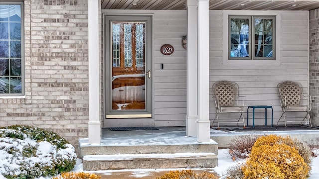 snow covered property entrance featuring a porch