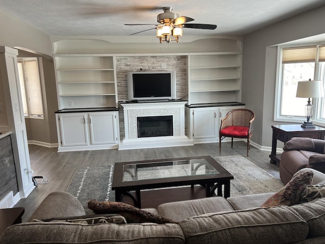 living room with ceiling fan, a textured ceiling, and light hardwood / wood-style flooring