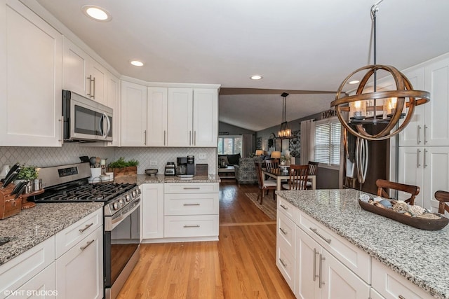 kitchen with an inviting chandelier, appliances with stainless steel finishes, white cabinetry, vaulted ceiling, and light wood-style flooring