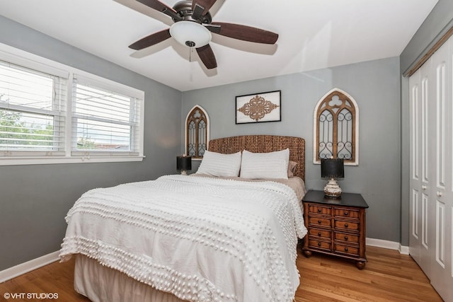 bedroom with light wood-type flooring, a closet, baseboards, and a ceiling fan