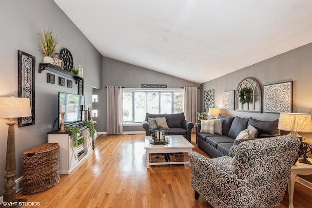 living room featuring baseboards, light wood-style floors, and lofted ceiling