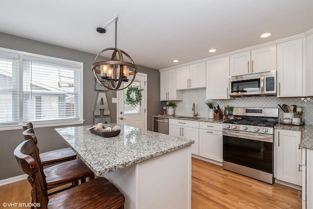 kitchen featuring a breakfast bar, a chandelier, white cabinetry, appliances with stainless steel finishes, and a sink