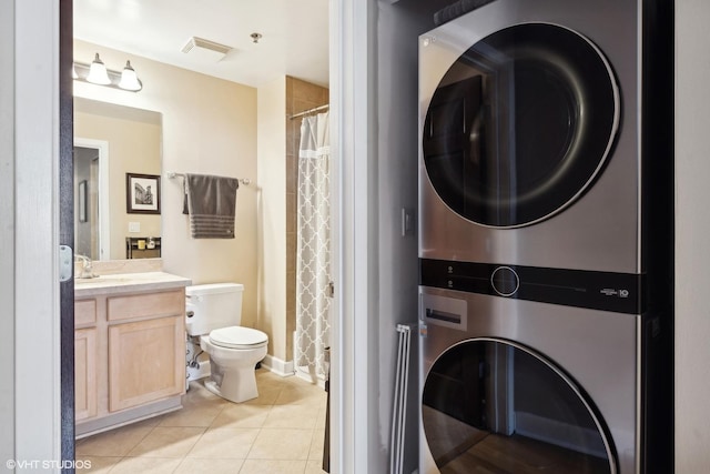 bathroom with toilet, vanity, tile patterned flooring, and stacked washer and dryer