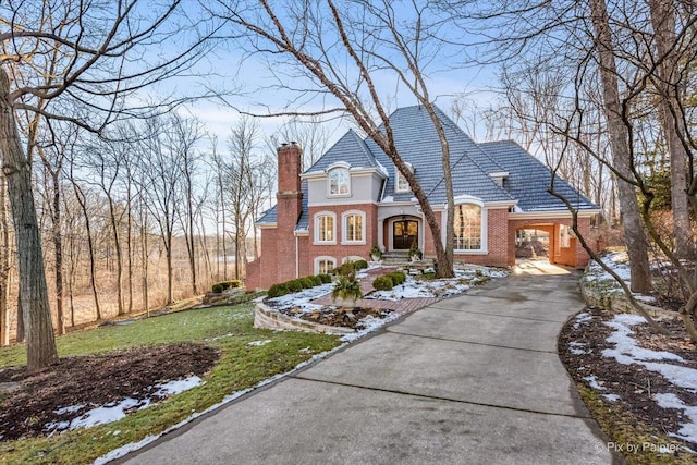 view of front of home with a chimney, a front lawn, concrete driveway, and brick siding