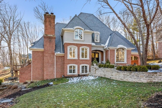 view of front of house featuring brick siding, a chimney, and a front yard