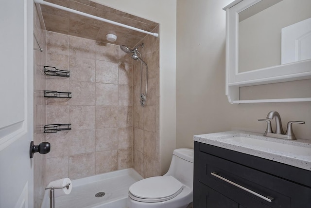 bathroom featuring vanity, tiled shower, and toilet