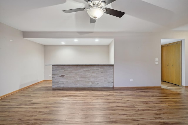 unfurnished living room featuring bar and light hardwood / wood-style floors