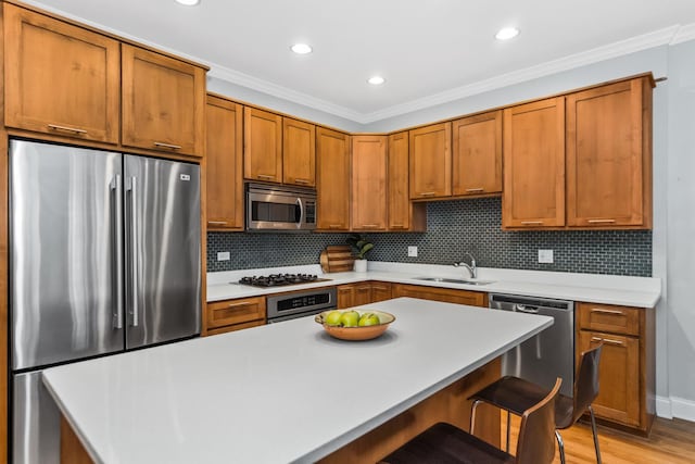 kitchen with a breakfast bar area, backsplash, stainless steel appliances, light countertops, and a sink