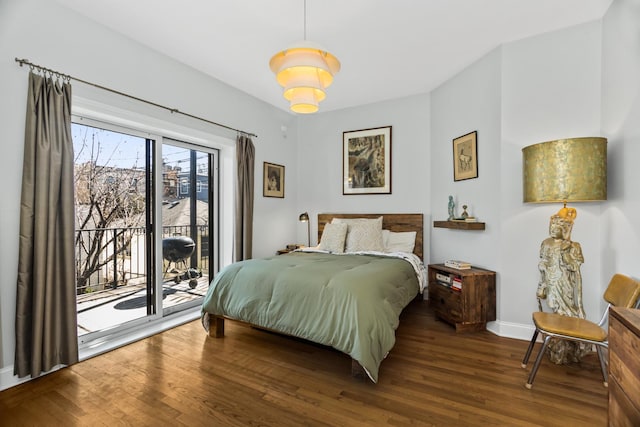 bedroom featuring access to exterior, baseboards, and wood finished floors