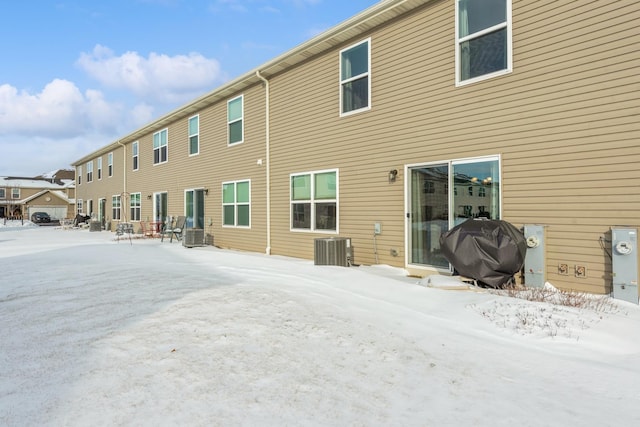 snow covered house featuring central AC unit