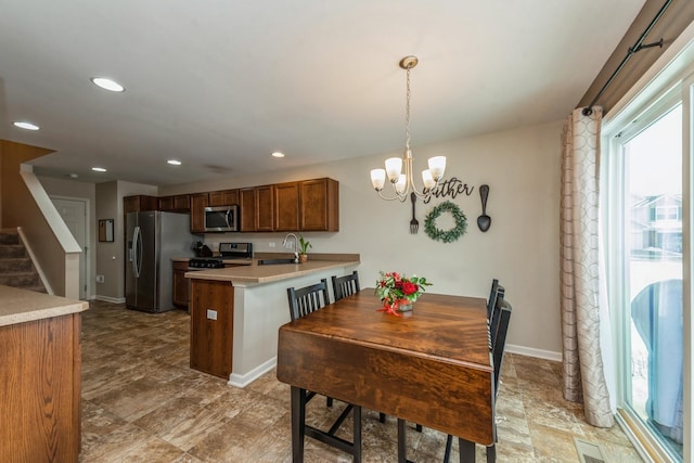 kitchen with appliances with stainless steel finishes, sink, a chandelier, hanging light fixtures, and kitchen peninsula