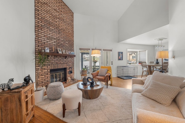 living room featuring a towering ceiling, plenty of natural light, a fireplace, and light wood-type flooring