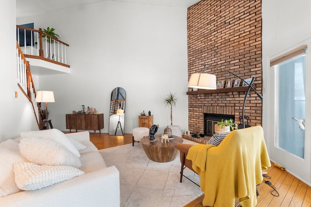 living room featuring a towering ceiling, a fireplace, and light wood-type flooring