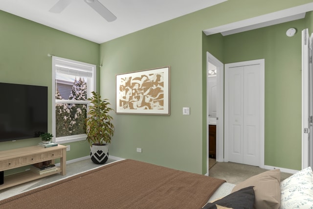 bedroom with a closet, light colored carpet, ceiling fan, and baseboards