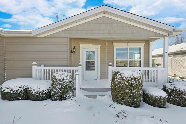 snow covered property entrance featuring covered porch