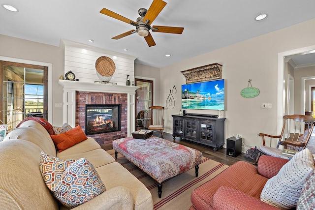 living room featuring hardwood / wood-style flooring, a brick fireplace, and ceiling fan