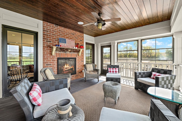 sunroom / solarium featuring an outdoor brick fireplace, ceiling fan, a healthy amount of sunlight, and wooden ceiling