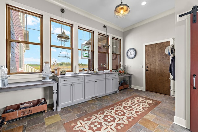 kitchen with a barn door, ornamental molding, decorative light fixtures, and sink