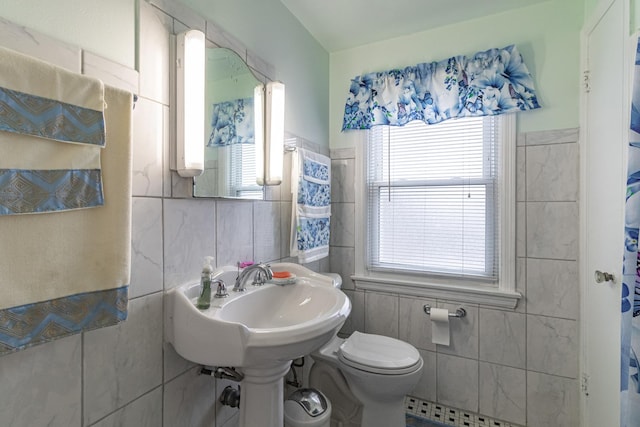 bathroom with a healthy amount of sunlight, tile walls, and toilet