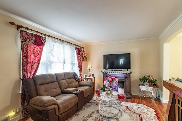 living area featuring arched walkways, crown molding, visible vents, wood finished floors, and baseboards