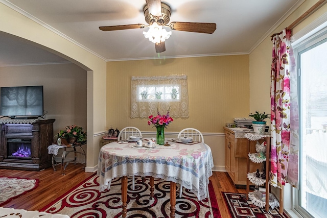 dining space with dark wood-type flooring, arched walkways, and crown molding