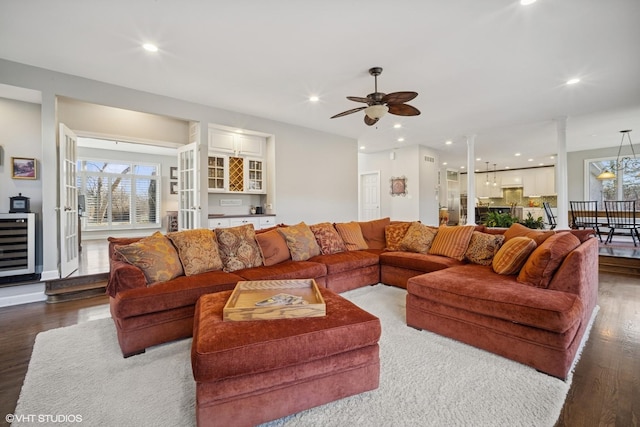 living room featuring ceiling fan with notable chandelier, wood finished floors, recessed lighting, wine cooler, and decorative columns