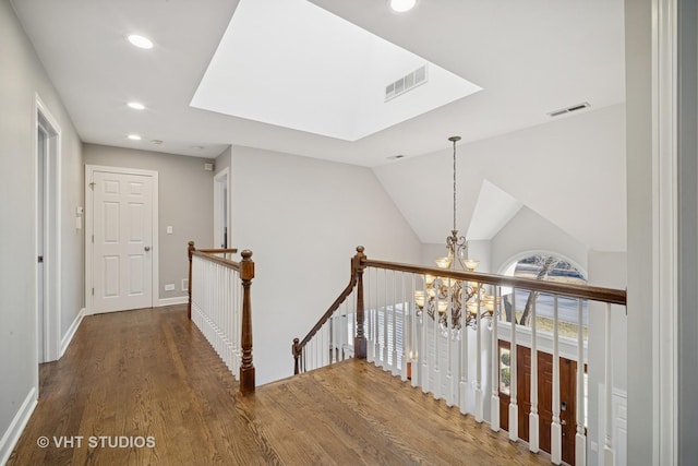 hallway with wood finished floors, visible vents, recessed lighting, an upstairs landing, and a chandelier