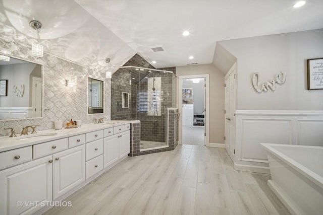 full bath with a sink, a freestanding tub, a stall shower, and double vanity