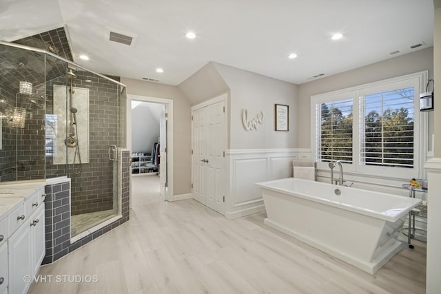 full bath featuring a shower stall, wainscoting, visible vents, and a freestanding bath