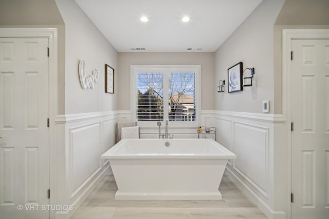 full bath featuring visible vents, recessed lighting, a wainscoted wall, and a freestanding tub